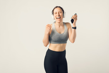 Photo of young beautiful girl listening music with headphones in the gym