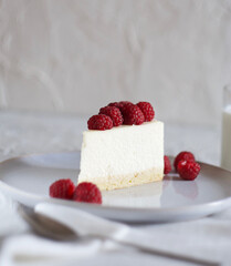 Piece of cheesecake on a saucer with raspberries on top
