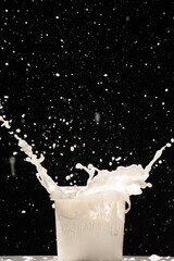 Splashing paint from a can. White paint splashing out of plastic can on black background
