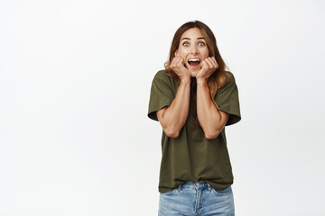 Image of excited and surprised adult woman scream from amazement and joy, checking out big surprise, awesome sale promo, standing against white background