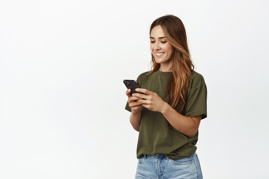 Image of smiling adult woman chatting in app, holding smartphone, looking at mobile phone screen happy, texting message, scroll shopping app, order smth in internet