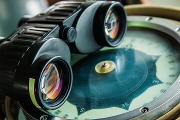 Optical binoculars lies on a gyrocompass, close-up.