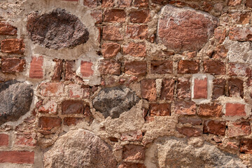 Part of a stone wall made of old bricks and boulders. Background or texture of old brick.