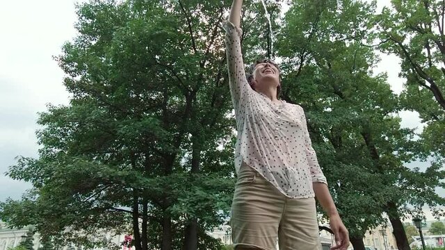 Young Woman Pouring Water From A Bottle On Herself In A Park On A Hot Summer Day. Slow Motion