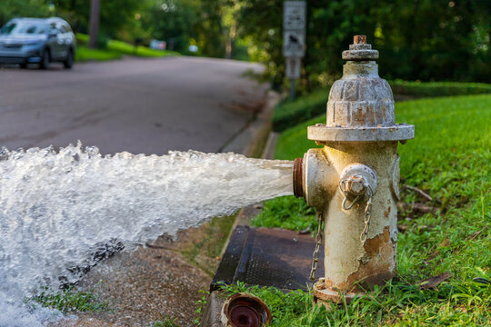Open fire hydrant gushing water onto street.