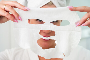 Beauty Skin Care Concept - Beautiful Caucasian Woman Applying Paper Sheet Mask On Her Face White