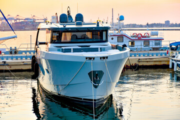 A white yacht is moored in the sea at the pier against the backdrop of the evening sunset.