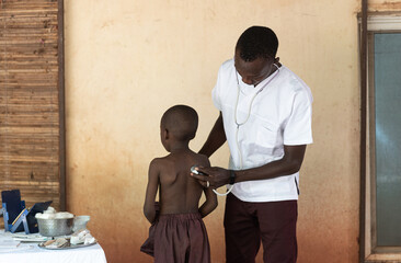 African doctor examining little young African black boy at hospital facility near Bamako, Mali.