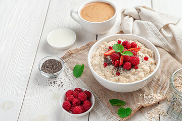 Healthy breakfast with oatmeal porridge with berries, mint and chia seeds.