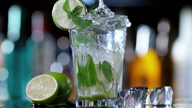 Super slow motion of falling ice cube into mojito drink, camera movement. Speed ramp effect. Filmed on high speed cinema camera, 1000 fps.
