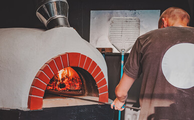 chef cookin pizza. Italian pizza is cooked in a wood-fired oven