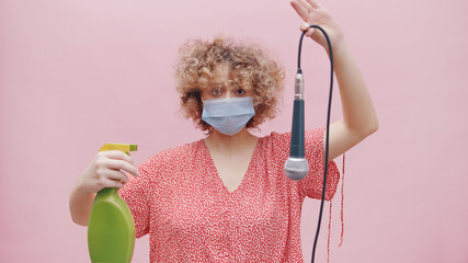 Girl wearing a face mask and a green spray bottle in her hand. Holding a mic upside down with its...