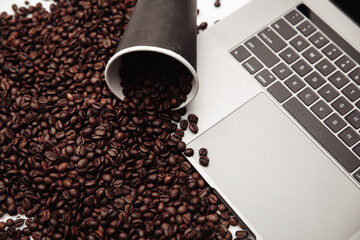 A cup of coffee on laptop and coffee beans