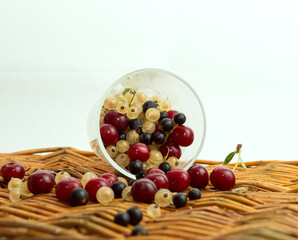 Mix of fresh berries in a basket on rustic wooden background