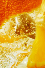 Macro view of sparkling lemonade with slices orange and ice cubes. Summer background.
