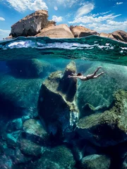 Printed kitchen splashbacks Half Dome Young girl swimming underwater in deep water. Woman in half underwater effect while she swims surrounded by huge rocks.
