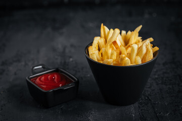 French fries with ketchup on a dark wooden rustic board