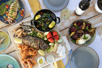 Top view on the table full of served seafood and vegetable dishes
