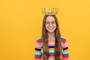 happy child in glasses wear queen crown on yellow background, victory
