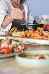 Young woman enjoying seafood platter during the sunset in the beach restaurant 
