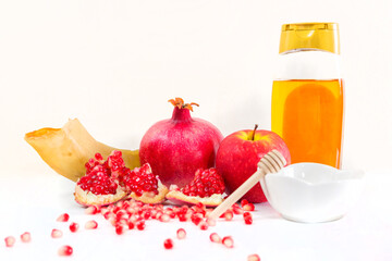 Whole pomegranate, pomegranate seeds, red apple, ram's horn and honey, on white background. Jewish New Year symbols.