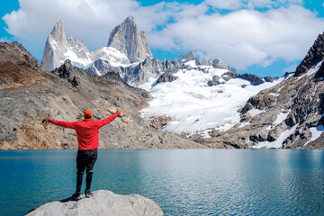 young man standing with open arms and staring to monte fitz roy and laguna de los tres happy