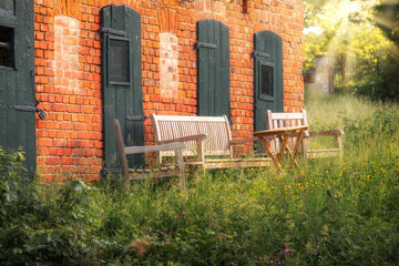 Wooden sofa set on the terrace in front of a red brick house in summer