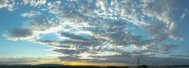 Panorama view on a moody yellow sunset between the clouds sky