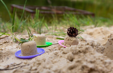 Children's game on the sandy beach, without people, the child made small figurines in the form of a cake. Children's entertainment in the summer.