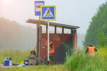 working painters paint a public transport stop