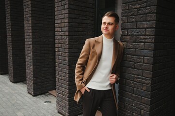 Portrait of a stylish man with a beard dressed in a coat, outdoors