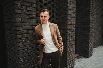 Portrait of handsome fashion businessman model dressed in elegant suit. Man posing on street background. Metrosexual