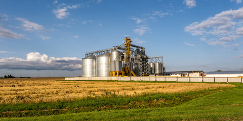 Fototapeta na wymiar Modern Granary elevator and seed cleaning line. Silver silos on agro-processing and manufacturing plant for storage and processing drying cleaning of agricultural products, flour, cereals and grain.