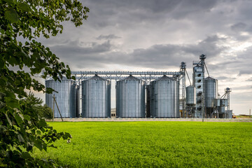 Modern Granary elevator and seed cleaning line. Silver silos on agro-processing and manufacturing plant for storage and processing drying cleaning of agricultural products, flour, cereals and grain.