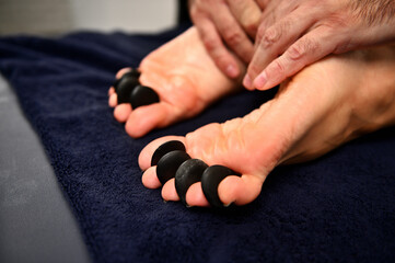Close-up of woman's feet receiving hot stone massage in Ayurvedic wellness spa-resort - obrazy, fototapety, plakaty
