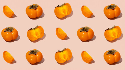 Colorful fruit pattern of fresh whole and sliced organic persimmon fruit with leaves on beige-pink background. Healthy eating and food concept. Flat lay, top view. Design element
