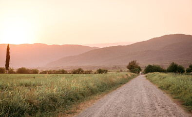 Dirt road through fields during sunset