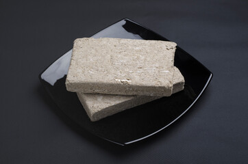 Sunflower halva. Halva is an oriental sweetness made from pounded sunflower seeds and caramel mass (sugar). Halva refers to the confectionery of the national oriental cuisine. Dark background, low key