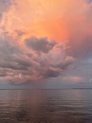 Burst of large colorful sunset clouds reflecting onto bay water