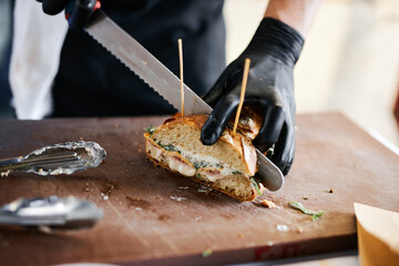 a chef with gloves cuts a french sandwich