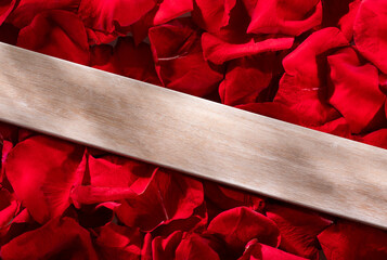 Wooden board on background of red rose petals