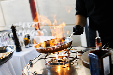 the chef prepares orange caramel on an open fire on the terrace of the restaurant