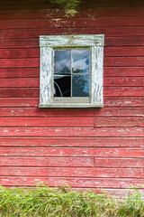Window on the wall of an old red barn.
