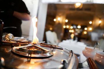 Naklejka premium the chef prepares orange caramel on an open fire on the terrace of the restaurant