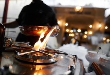 the chef prepares orange caramel on an open fire on the terrace of the restaurant