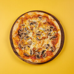 rustic pizza with mushrooms on wooden board and yellow background