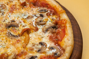 rustic pizza with mushrooms on wooden board and yellow background