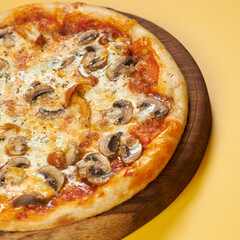 rustic pizza with mushrooms on wooden board and yellow background