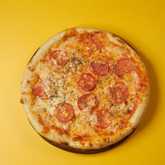 rustic pizza with tomatoes on wooden board and yellow background