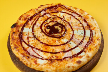 rustic bbq pizza with chicken and ham on wooden board and yellow background